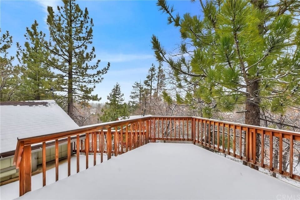 A snow-covered deck opens up to sweeping views of the surrounding pines and rooftops below. A peaceful spot to take in the mountain scenery.