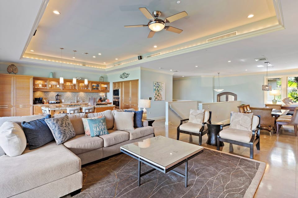 Wailea Hoolei 93-3 offers a spacious living area with a plush sectional, modern fan, and seamless flow into the kitchen.