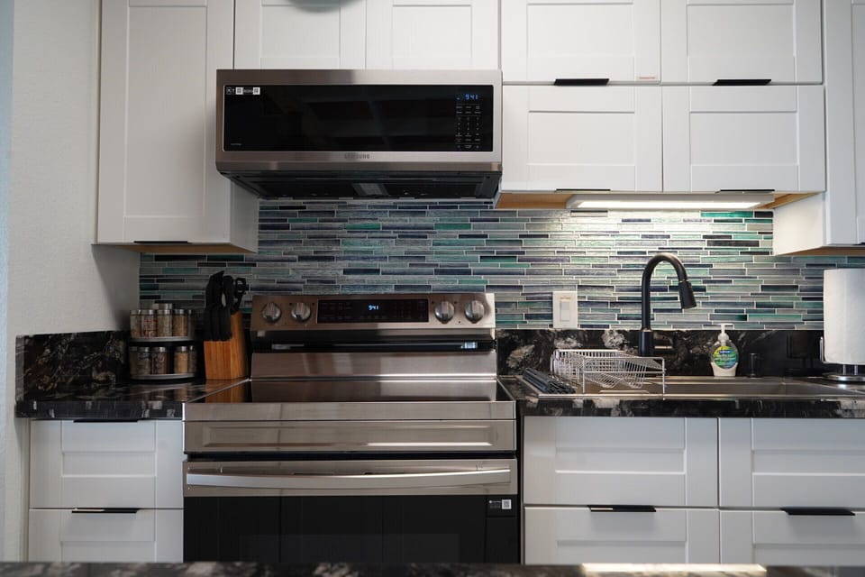 Modern kitchen with stainless appliances, sleek finishes, and stylish tile backsplash