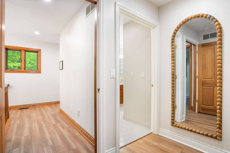 Entryway into the primary bedroom suite with a large floor length mirror for getting ready, between the bathroom and walk-in closet. 