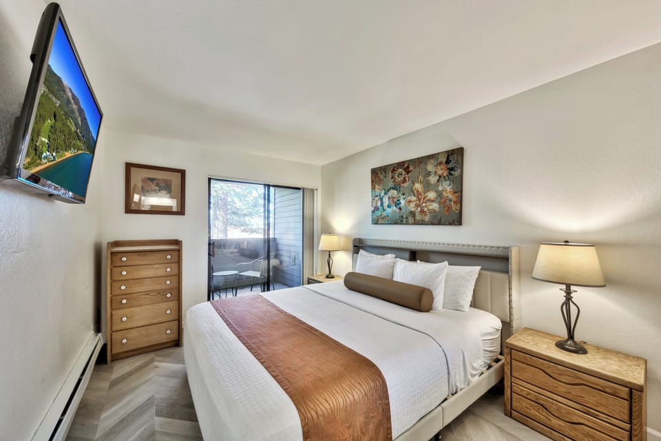 Unwind in your comfortable bedroom with hotel-quality linens, private balcony access, and modern amenities like a wall-mounted TV.