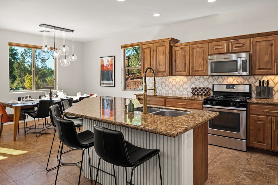 Barstools pop against the white wood paneling and large granite kitchen island