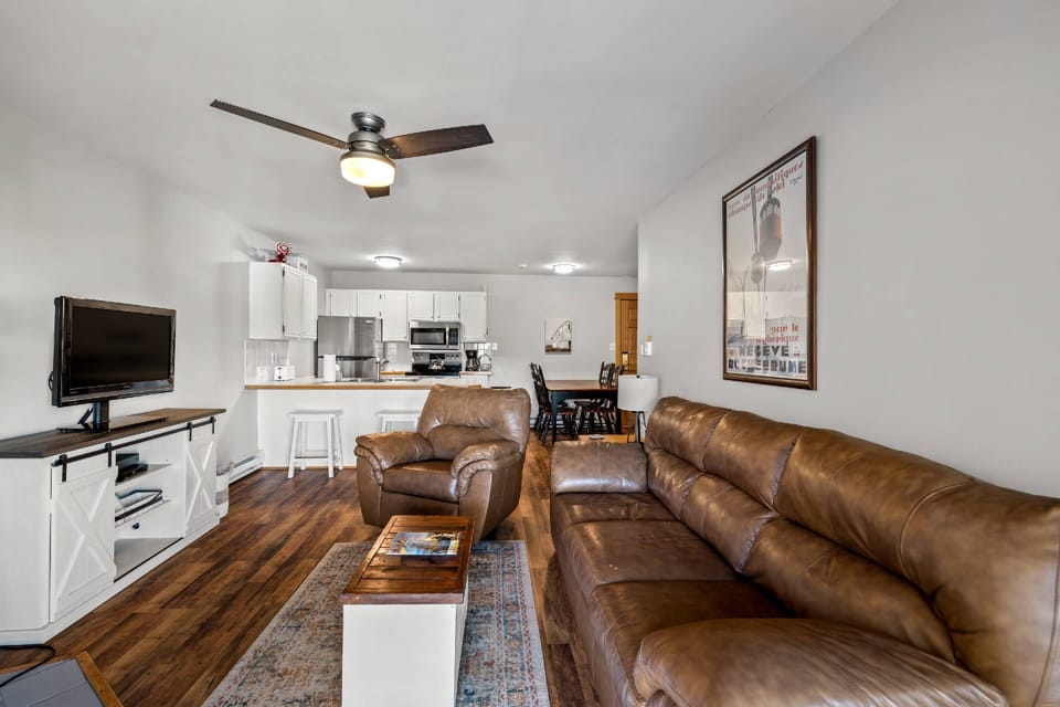 Open floor plan featuring comfy sofas, a TV, and a fully equipped kitchen—perfect for relaxing and entertaining.