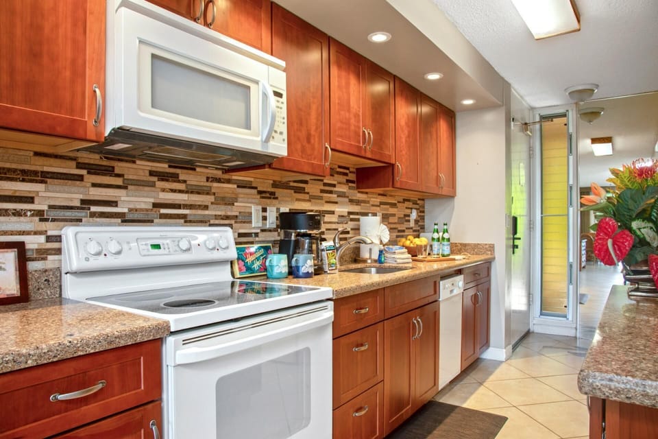 This charming kitchen mixes rich cherry cabinets, a mosaic backsplash, and countertop cheer that’s ready to serve joy   