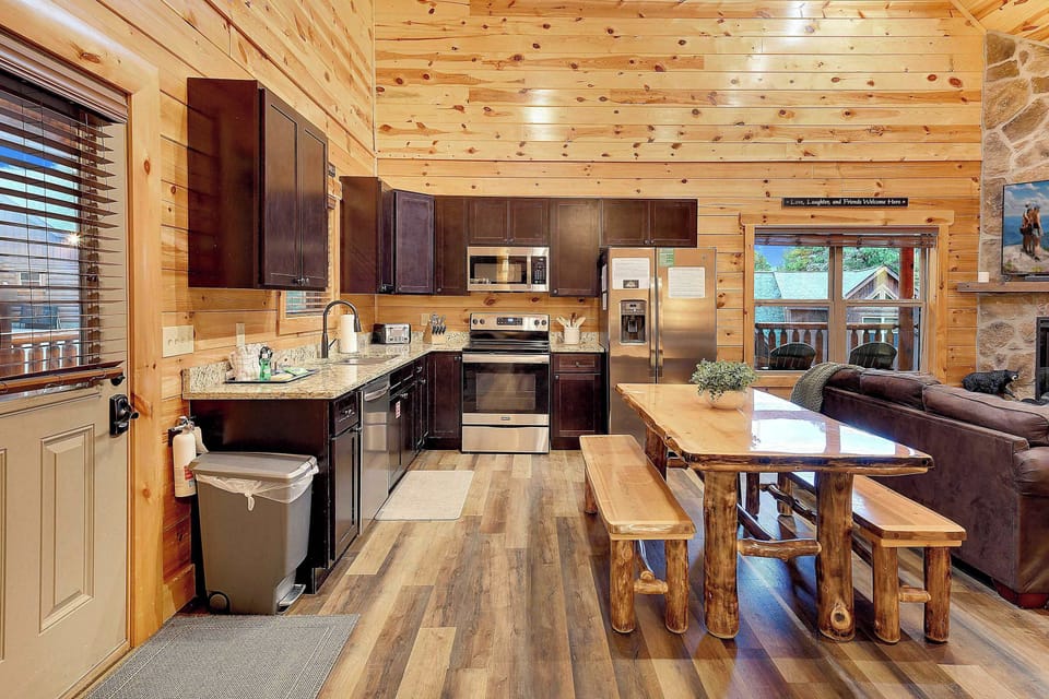 rustic kitchen with dark cabinetry and a natural wood dining table in a cozy cabin setting