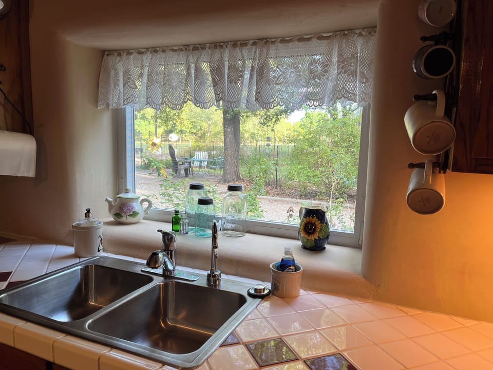Kitchen sink window overlooking outdoor seating and parking area