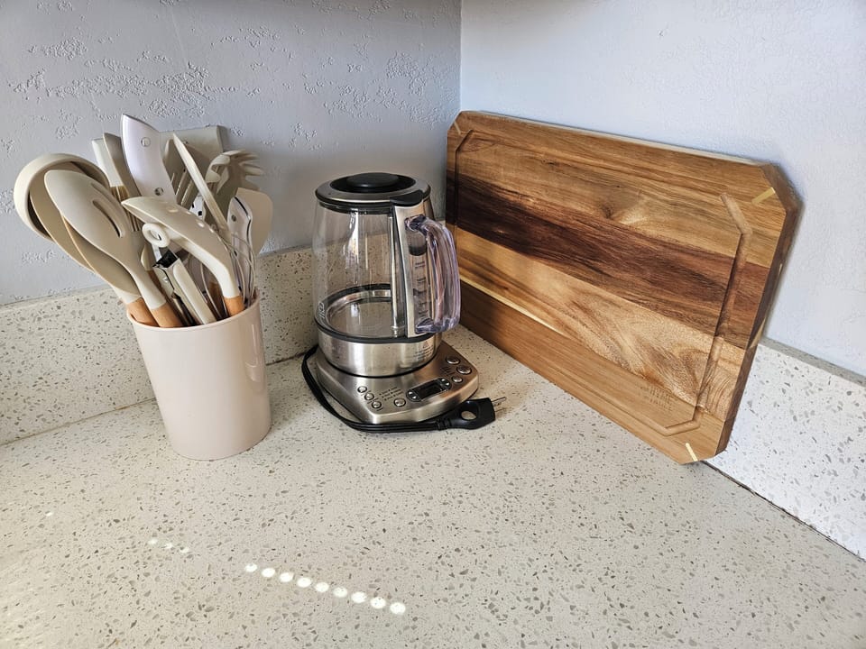 Cooking utensils, tea kettle and cutting board are ready for your next meal! 