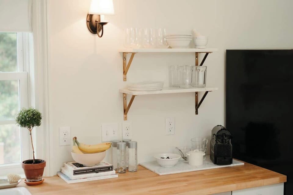 Open shelving with glassware and dishware, plus a Nespresso machine and starter pods for your morning coffee.