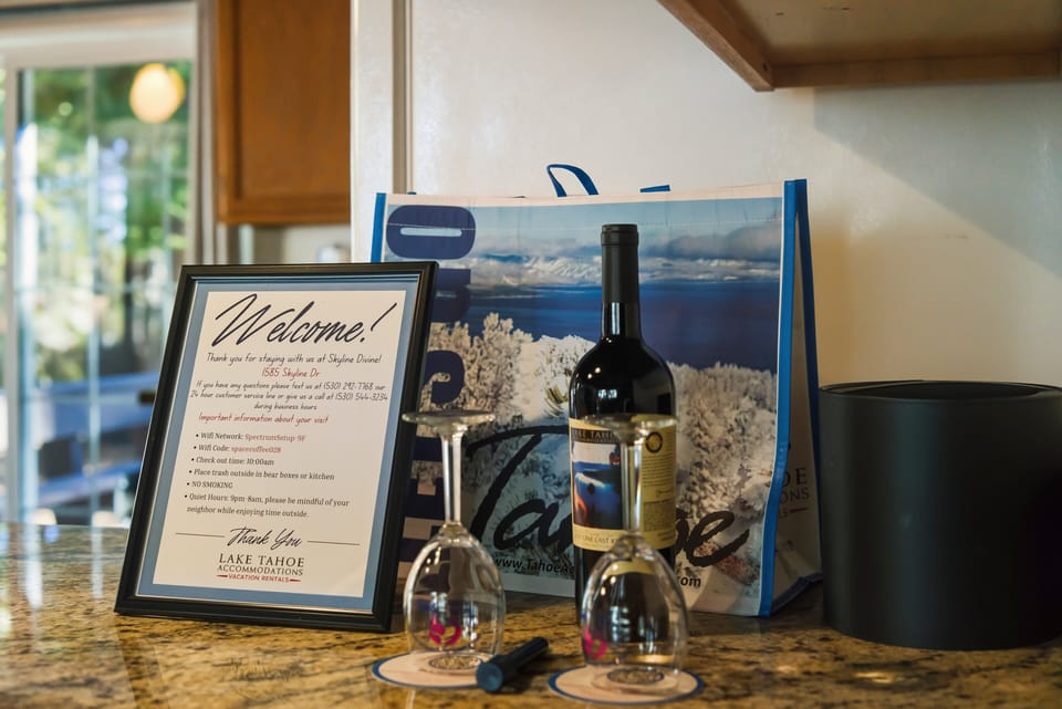 Kitchen counter welcome setup with framed note, bottle, drinkware, tote bag, and ice bucket.