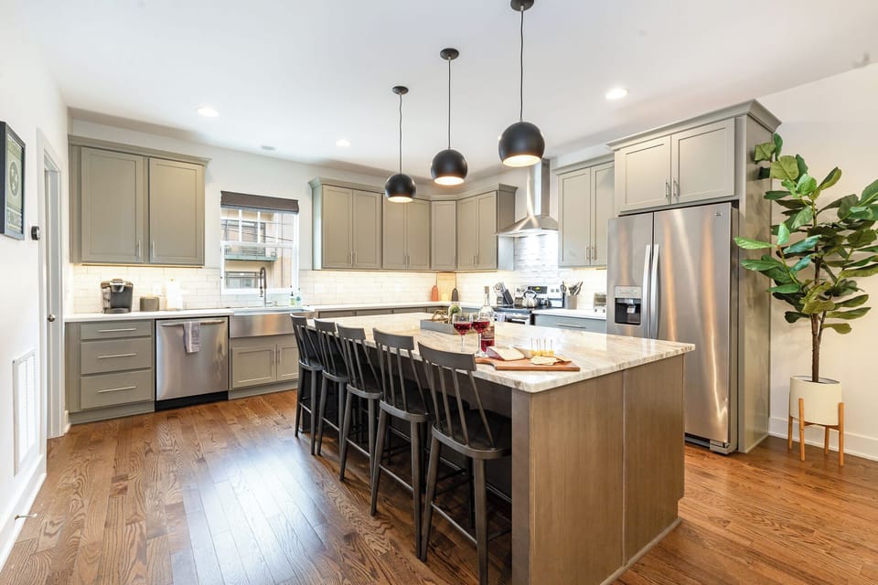1st Floor: The fully equipped modern kitchen features culinary essentials, stainless steel appliances, and island bar seating.