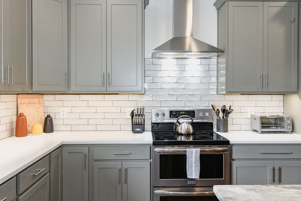 1st Floor: The fully equipped modern kitchen features culinary essentials, stainless steel appliances, and island bar seating.