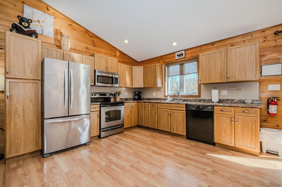 A warm, wood paneled kitchen with stainless steel appliances, ample cabinet space, and granite countertops. The open layout creates a cozy, inviting atmosphere.
