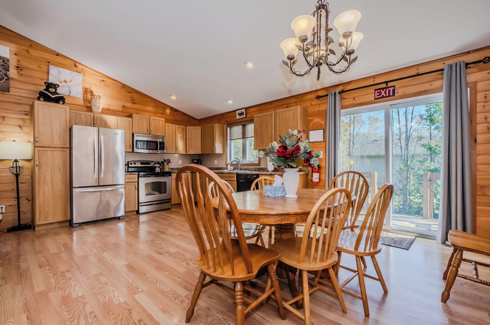 The spacious kitchen and dining area is perfect for family gatherings, featuring modern stainless steel appliances and ample counter space for preparing meals. The dining table seats six comfortably, with plenty of natural light flowing in through the patio doors that lead to the back deck, ideal for BBQs or enjoying outdoor meals.