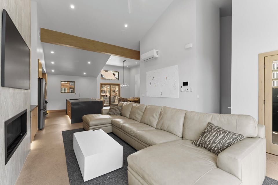 Sink into plush leather seating in your sleek modern living space, where vaulted ceilings and warm wood accents create the perfect retreat.