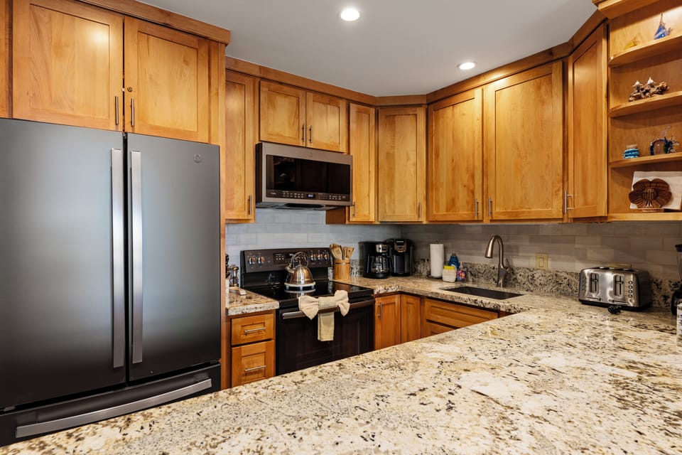 Spacious kitchen featuring modern stainless-steel appliances and granite countertops, ideal for cooking gourmet meals with ocean views right from your vacation rental.