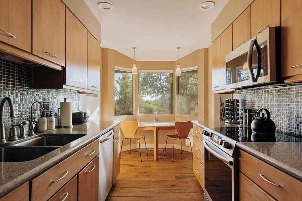 Your fully-equipped kitchen boasts modern appliances and a cozy breakfast nook where you can savor morning coffee with tree views.
