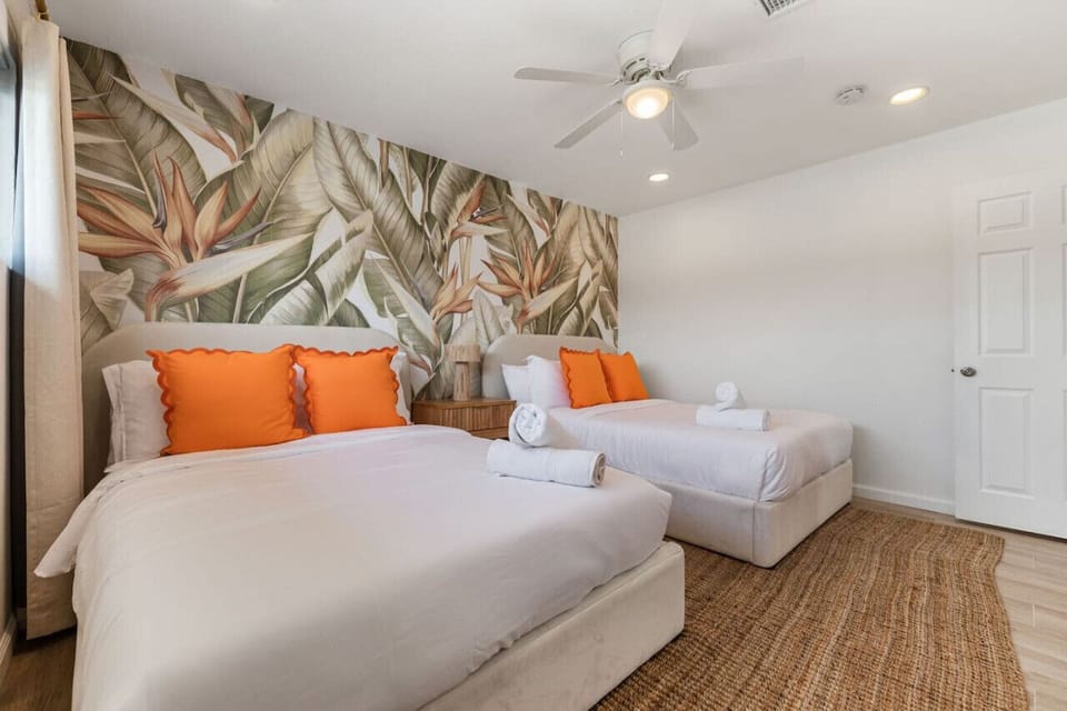 Bright bedroom w/ twin beds, bold accent pillows, and playful wall art.