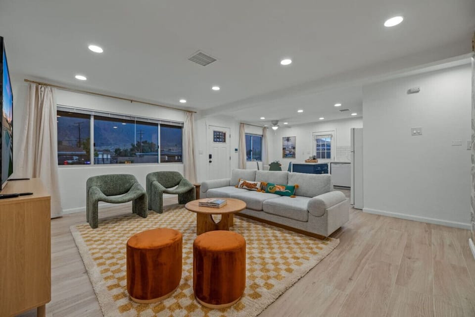 Bright open living room w/ comfy seating and modern decor, ideal for relaxing or gathering together.