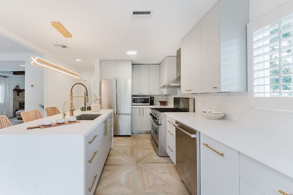 This spacious, modern kitchen features sleek white cabinetry and a bright, open layout. The contemporary design invites creativity and makes cooking a pleasure.