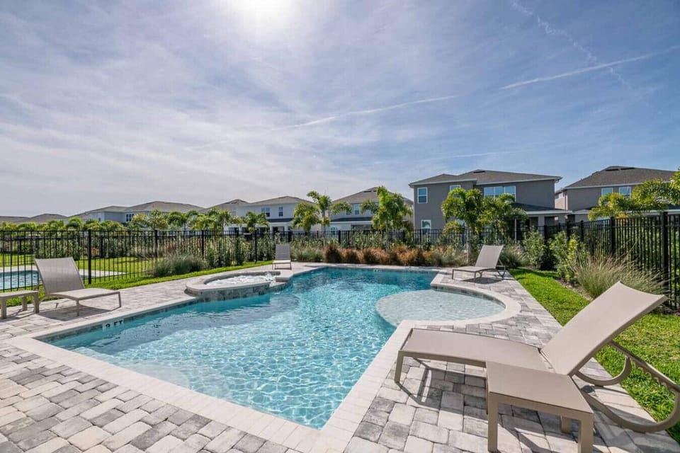 Heated spa and pool view with sunbathing chairs