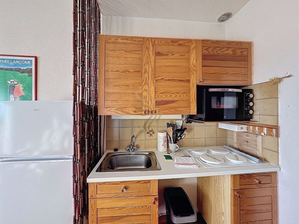 Cette cuisine compacte invite à la simplicité sans sacrifier l'essentiel. Derrière le rideau en bambou, un espace supplémentaire pourrait être caché, offrant plus de rangement ou un coin repas. Parfaite pour préparer un repas sans complications.