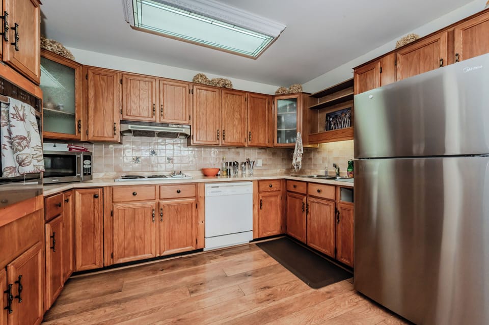 This spacious kitchen combines modern conveniences with rustic charm. The warm wooden cabinetry, ample counter space, and stainless steel appliances create a perfect environment for preparing meals. A built-in oven and microwave add to the kitchen’s functionality, while the adjacent dining nook is ideal for sharing a home-cooked meal or morning coffee with a view.