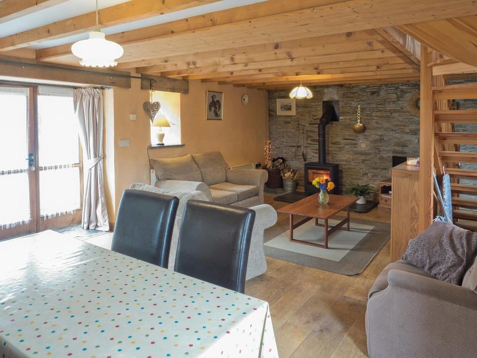 Open plan living/dining area with sofas, coffee table, dining chairs, sofas, log burner and open tread stairs