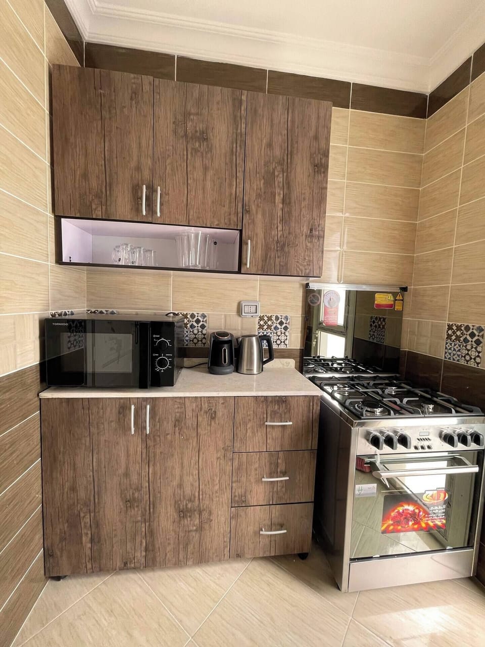 A small kitchen with a stove, oven, refrigerator and microwave