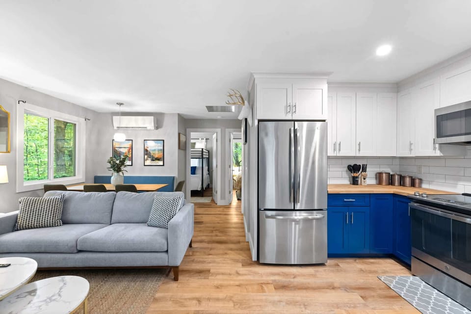 Modern kitchen and living area with blue cabinetry and natural light from large windows
