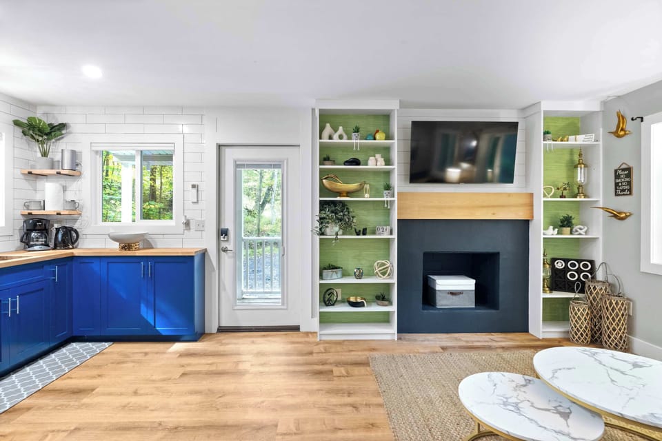 Modern kitchen and living area with blue cabinetry and a built-in fireplace under a mounted television.