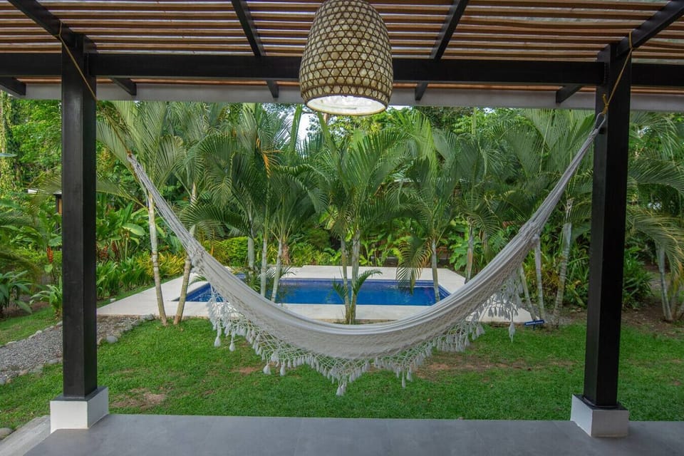 Hammock overlooking the pool surrounded by lush tropical garden, Tres Lodge Villa in Playa Chiquita, Costa Rica