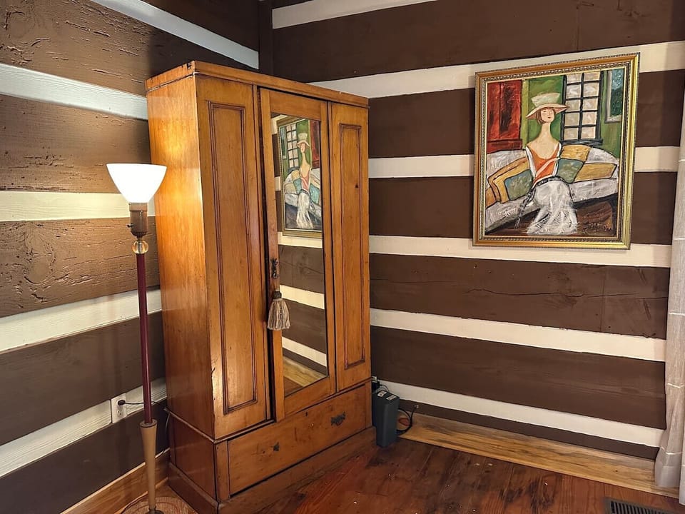 Spacious master bedroom offering a king bed, armoire, full bath, and French doors to the covered back porch.