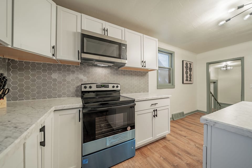 - Fully equipped kitchen with modern appliances and marble counters   - Stainless steel oven microwave and hex tile backsplash design   - Warm wood flooring and bright lighting for a perfect cooking space