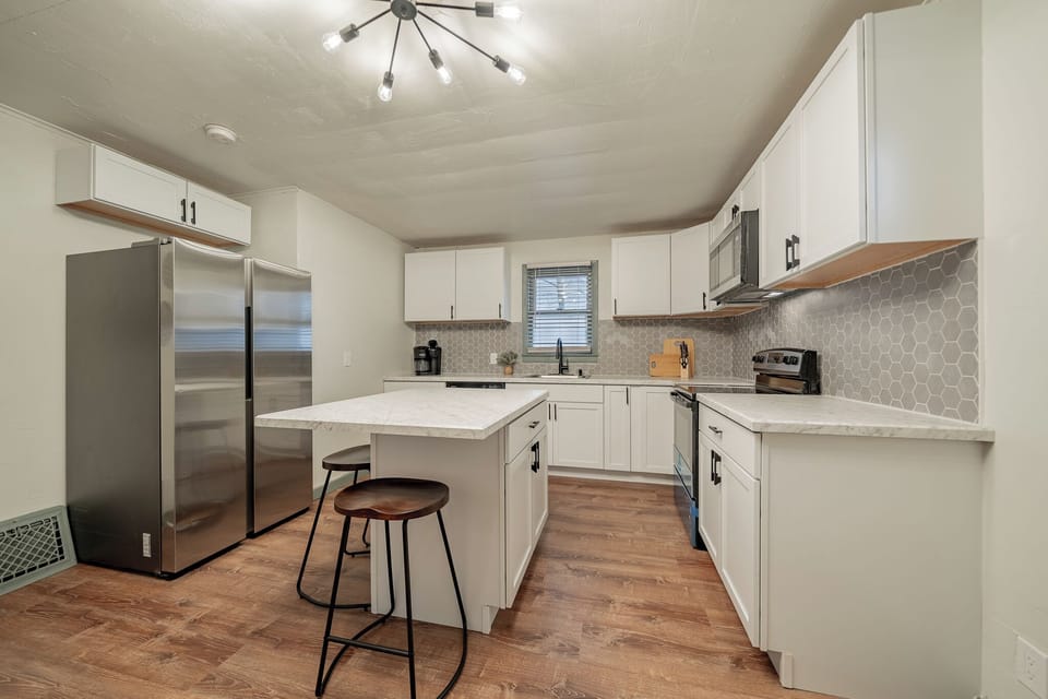 - Modern kitchen with stainless steel appliances and sleek white cabinets   - Central island with seating ideal for quick meals or casual chats   - Hardwood flooring and stylish lighting elevate the cooking experience