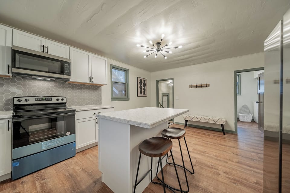 - Open kitchen design featuring stainless steel appliances and island seating   - Sleek lighting fixture adds a modern touch to your cooking space   - Perfect layout for meal prep or morning coffee with natural light