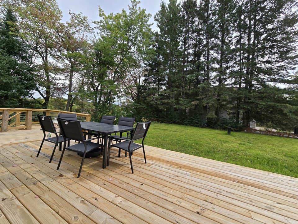 - Dine outdoors on this wide deck with forest views   - Comfortable seating makes meals feel refreshing   - A serene backyard setup perfect for gatherings