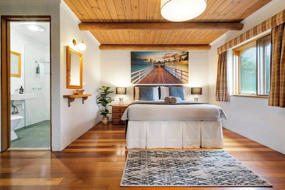 Escape to your private sanctuary in this elegantly appointed bedroom area, featuring a plush queen bed and timber floorboards. The half-wall partition offers a sense of separation from the open living area, creating a serene retreat.