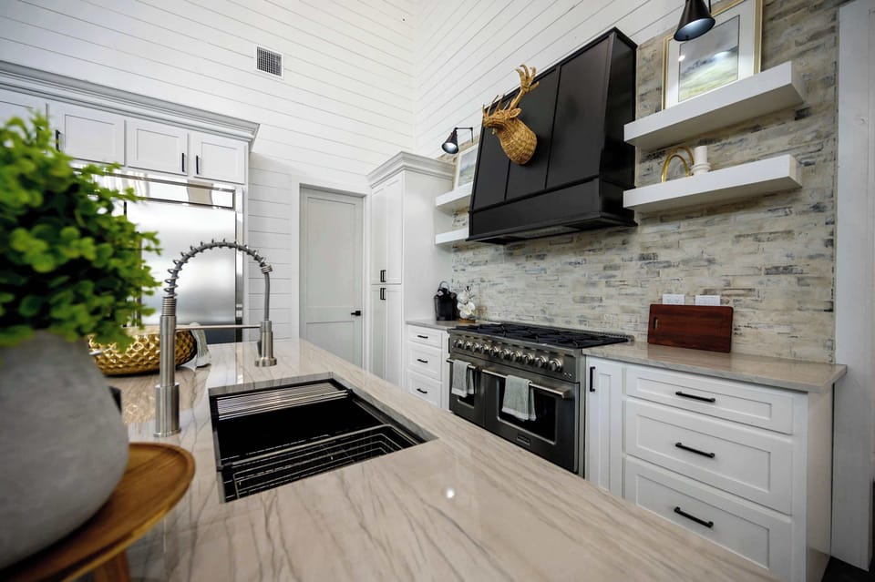 Elegant kitchen with marble countertops, farmhouse sink, and premium stainless steel appliances in upscale cabin