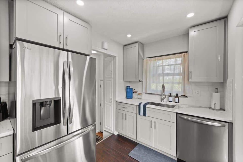 Bright kitchen w/ farmhouse sink, white cabinetry & window views