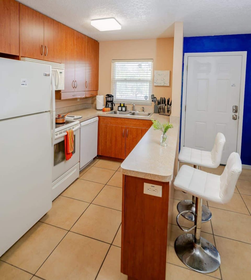 Fully equipped kitchen featuring wooden cabinetry, appliances, and a convenient breakfast bar with seating.