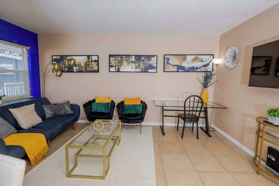 A spacious living area with contemporary furnishings, including blue and yellow seating, and tasteful wall art.