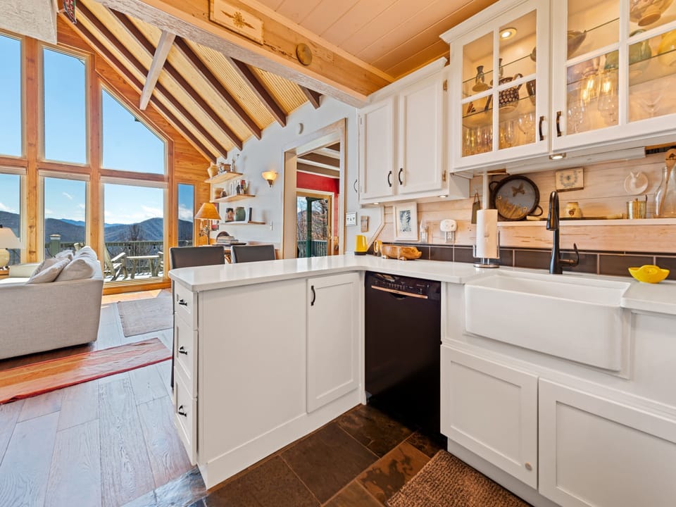 Bright kitchen with farmhouse sink, white cabinets, and mountain views.