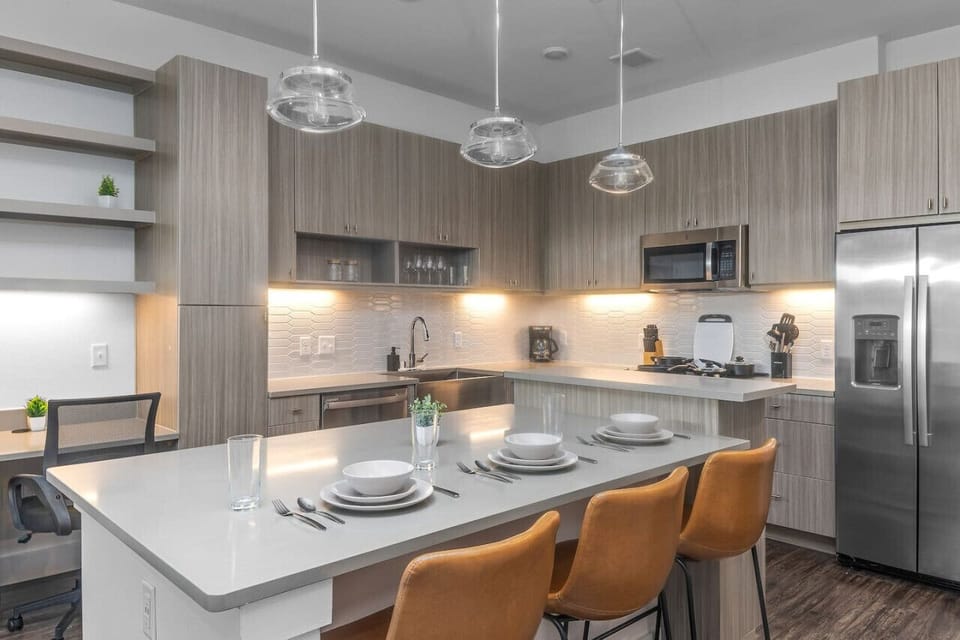 Prepare meals in this modern, fully-equipped kitchen featuring stainless steel appliances and a spacious island with bar seating. The open layout makes it easy to cook and entertain, ensuring a delightful culinary experience during your stay.