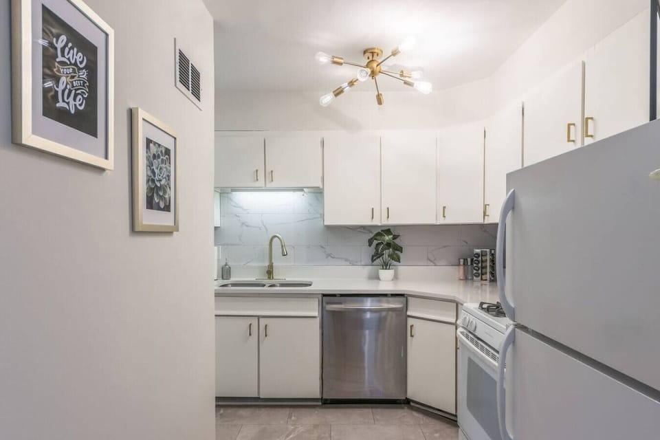 Fully equipped kitchen with crisp white cabinets, stainless steel appliances, and stylish gold hardware. Includes dishwasher, gas stove, and full-size fridge…perfect for home cooking or quick meals during your stay.