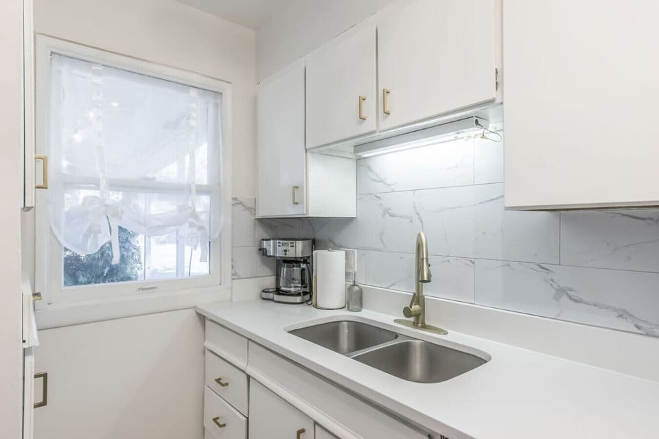 Fully equipped kitchen with crisp white cabinets, stainless steel appliances, and stylish gold hardware. Includes dishwasher, gas stove, and full-size fridge…perfect for home cooking or quick meals during your stay.