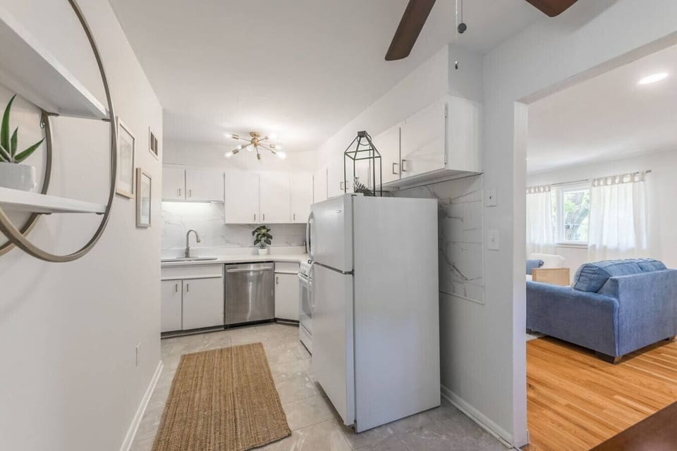 Fully equipped kitchen with crisp white cabinets, stainless steel appliances, and stylish gold hardware. Includes dishwasher, gas stove, and full-size fridge…perfect for home cooking or quick meals during your stay.