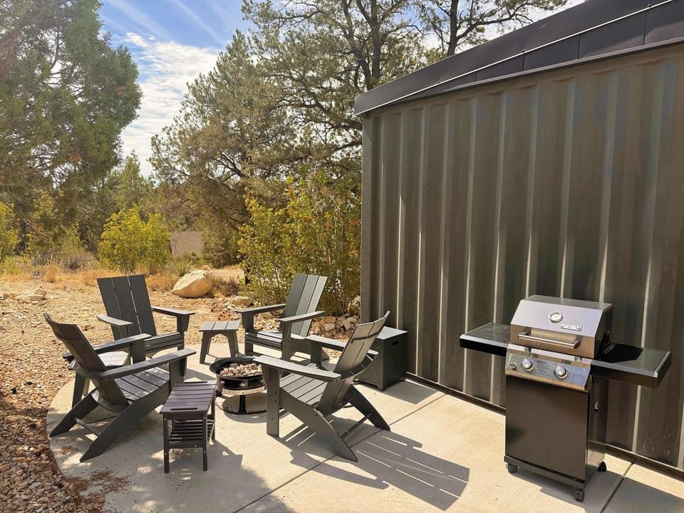 Private outdoor seating area nestled in the trees with a BBQ grill, gas fire pit, and stargazing at night during your peaceful Southern Utah cabin stay.
