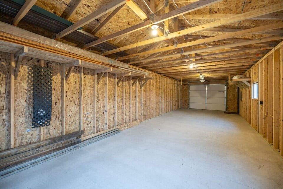 The garage offers ample space for vehicle storage and additional storage solutions, featuring organized shelves and a clean, functional layout that enhances convenience and accessibility.