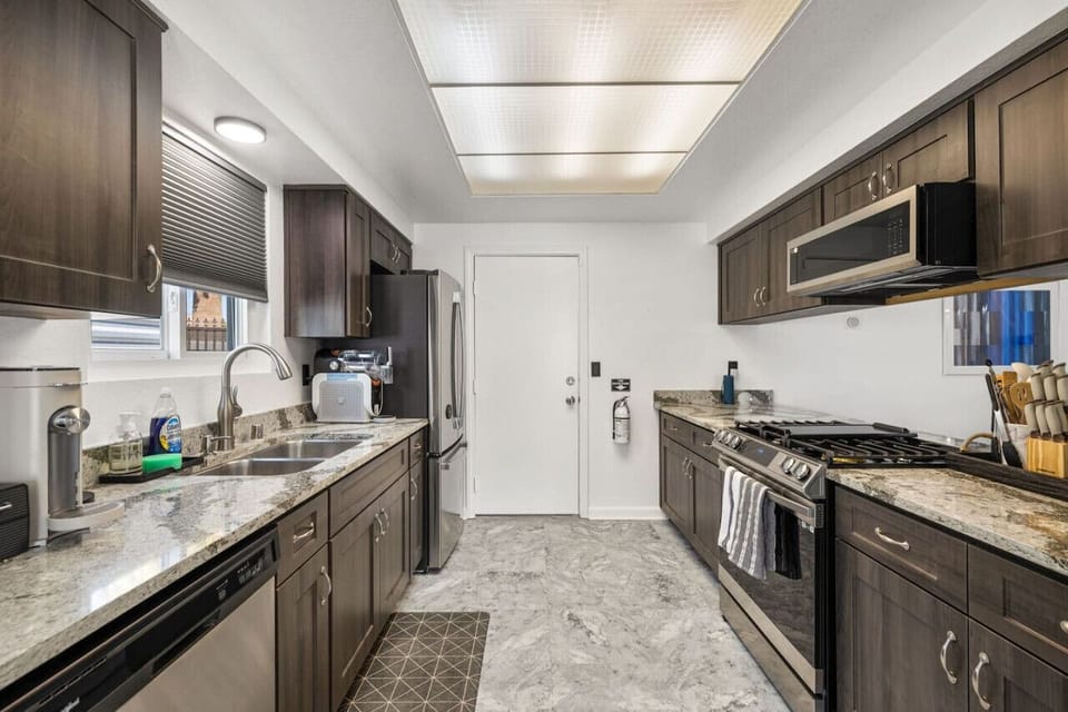Sleek galley kitchen w/ stone counters, modern appliances, and streamlined layout for easy cooking.