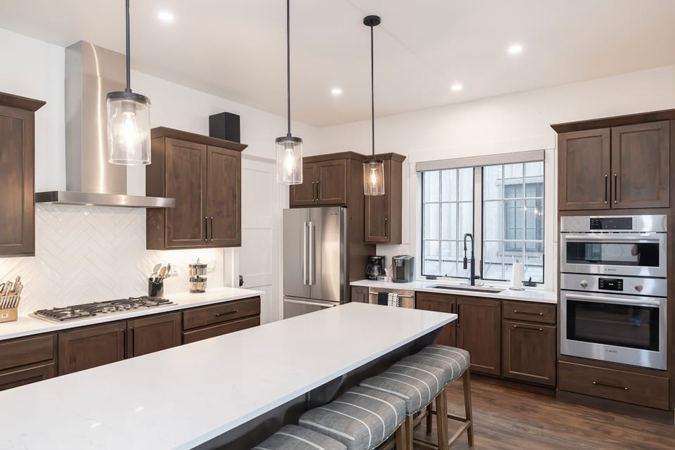 - This bright, modern kitchen boasts stainless steel appliances, a spacious island with seating, and warm wood cabinetry, making it perfect for cooking and entertaining. Sleek lighting and large windows add to the inviting atmosphere.
